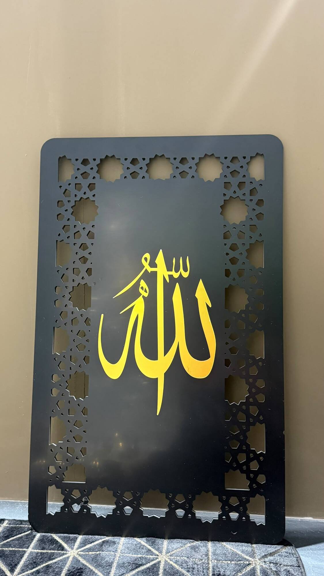 Black wall panel with gold Allah calligraphy and a cut geometric border