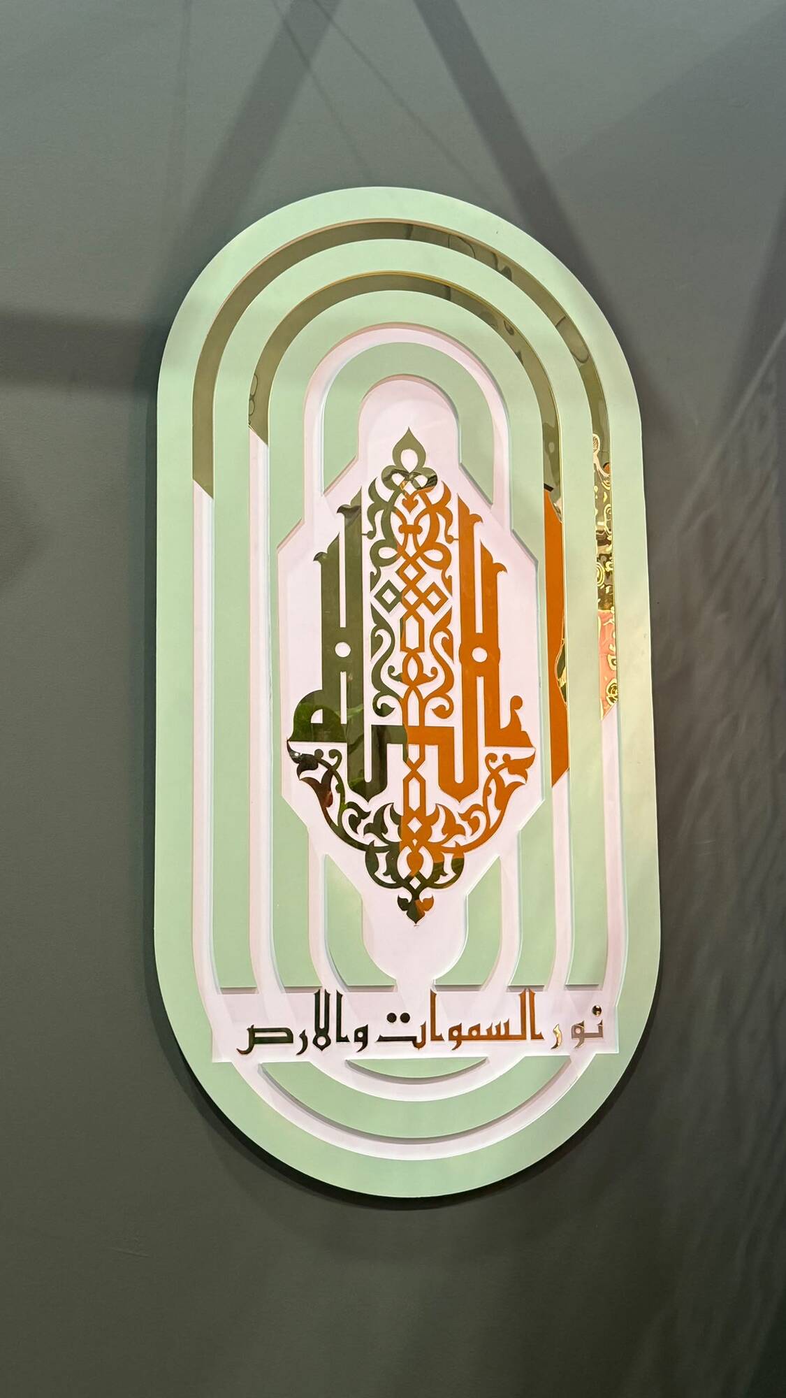 Sage green and gold layered oval wall panel with mirrored calligraphy