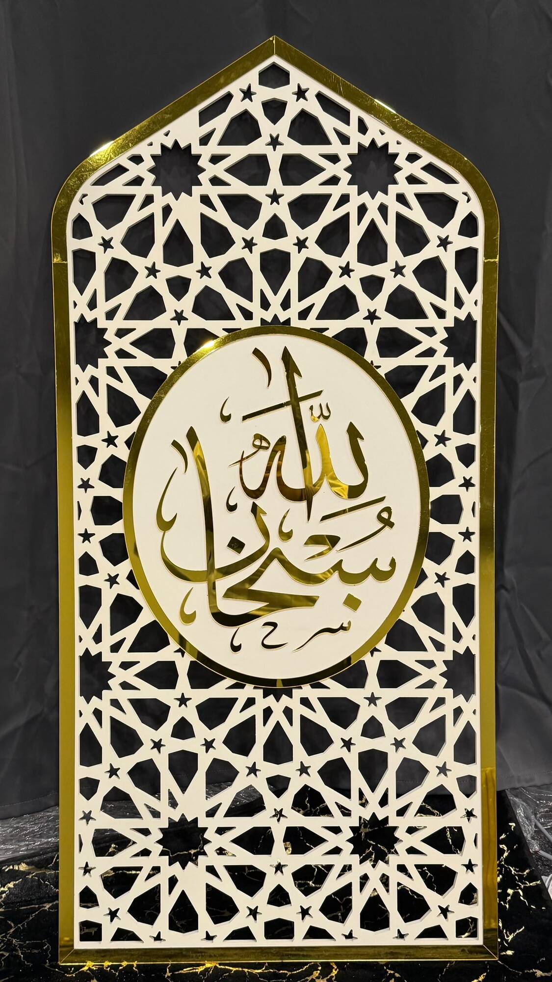 White and gold mihrab arch panel with cut geometric lattice and a gold Subhanallah medallion