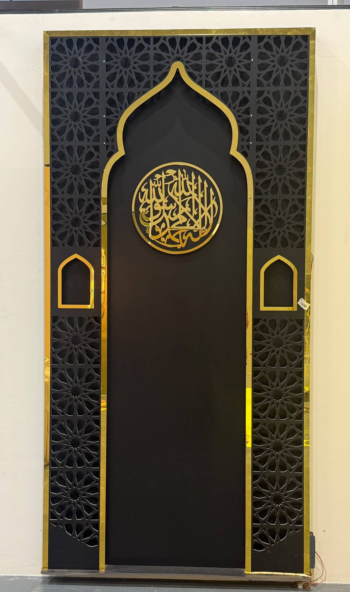 Full-height black and gold mihrab with gold medallion and arched side doors
