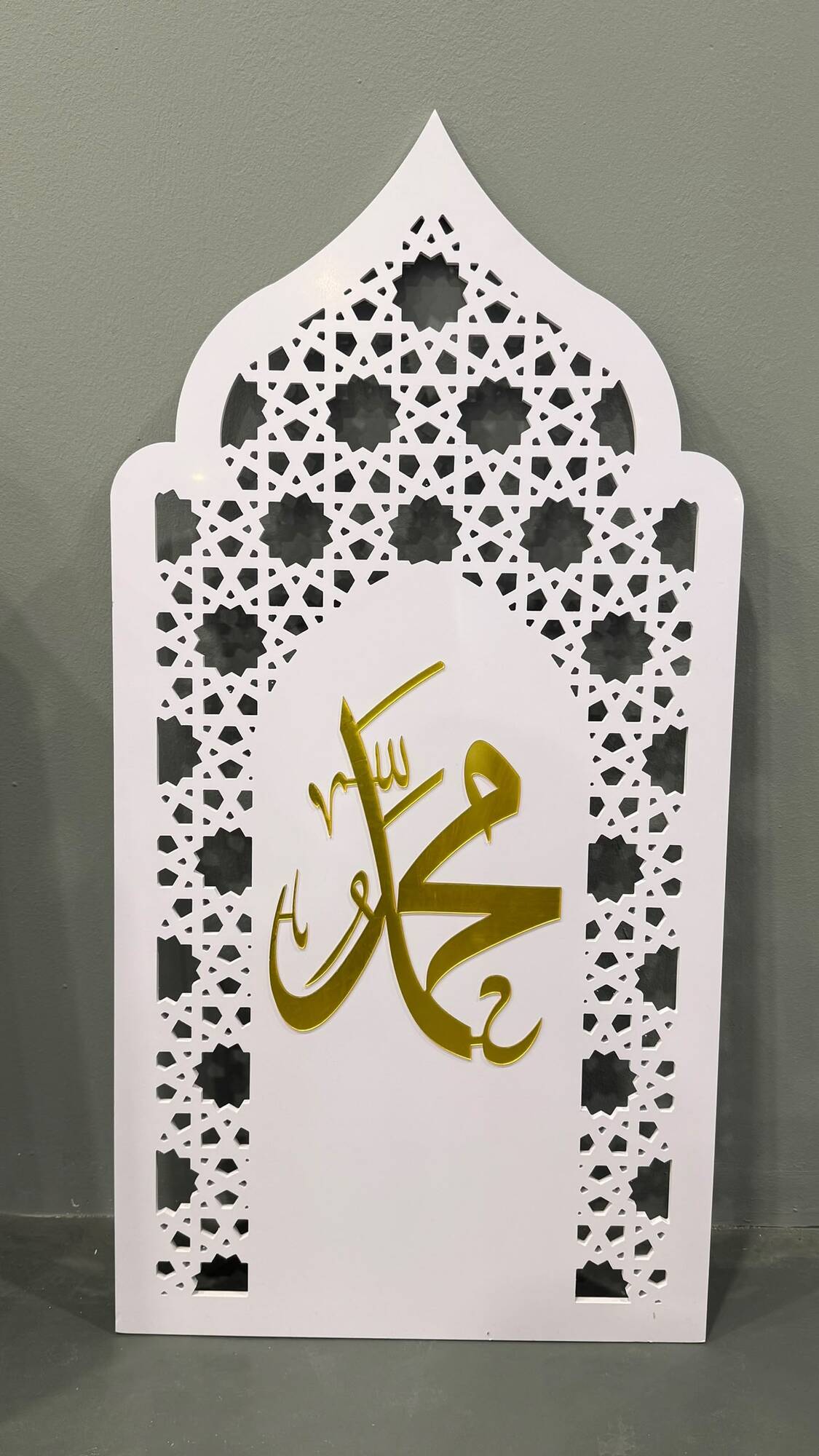 White ogee-arch mihrab panel with gold Muhammad calligraphy and geometric lattice