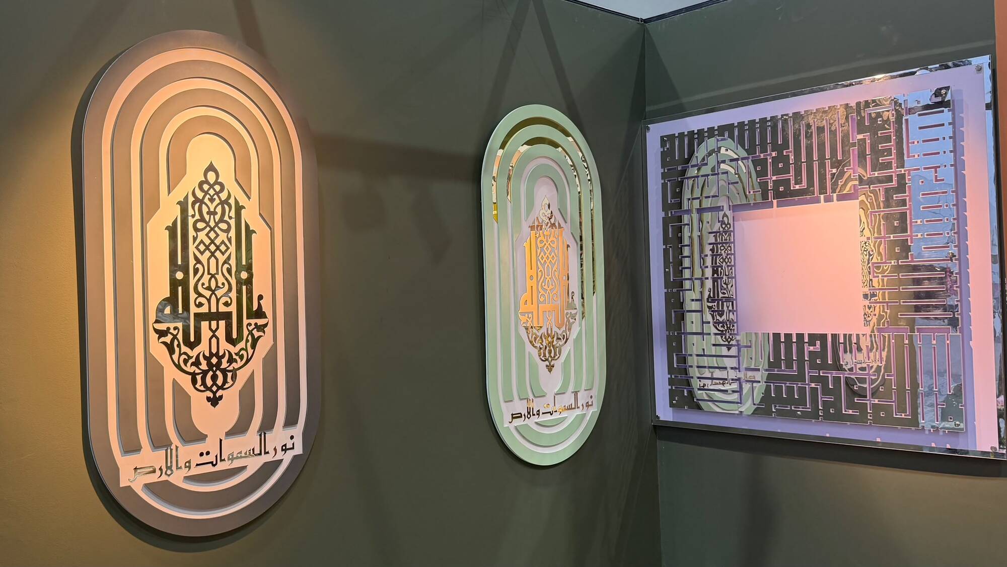 Three backlit calligraphy panels glowing on a dark showroom wall