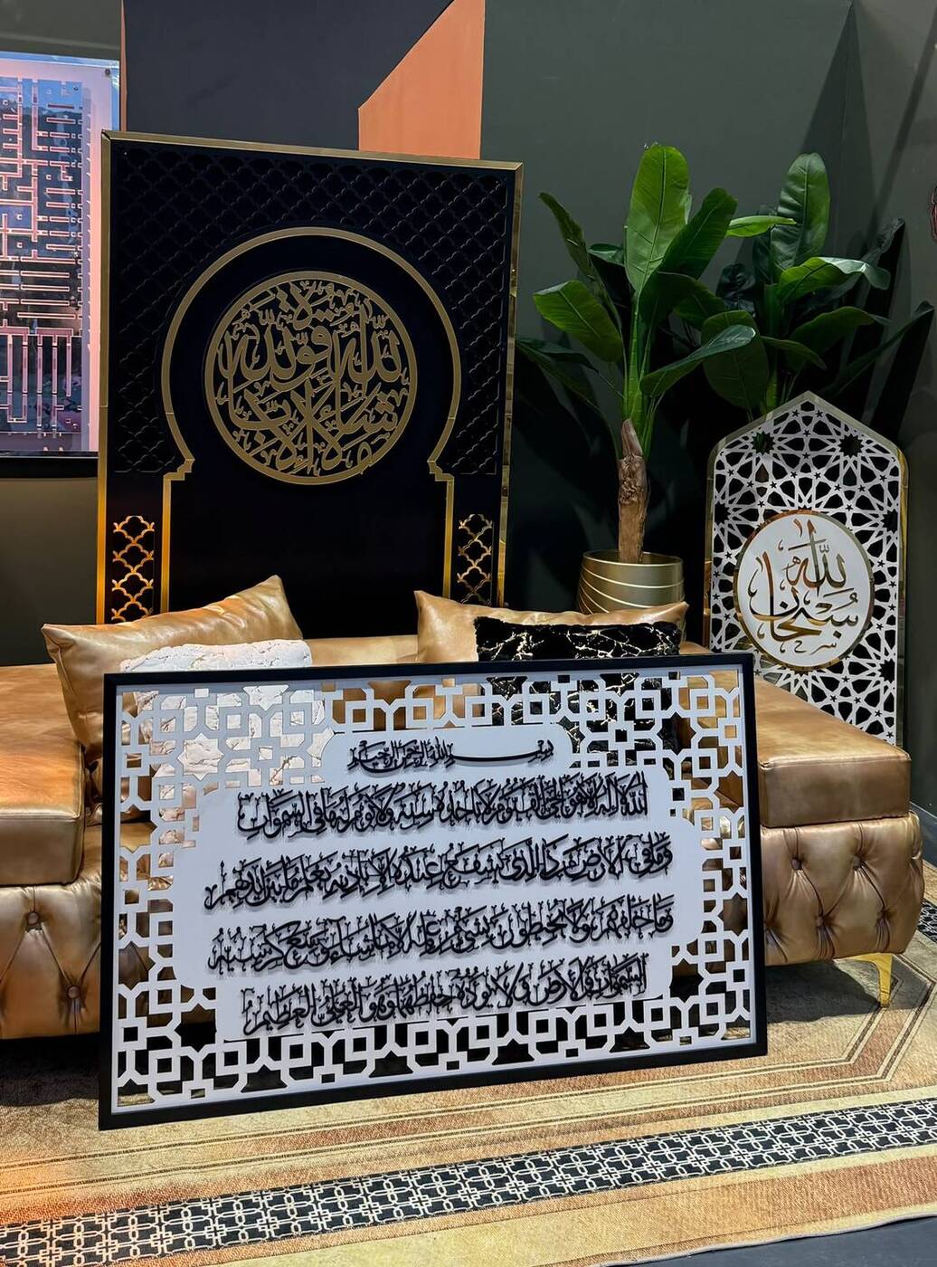 Showroom vignette with a black and gold arch panel, seating and framed calligraphy